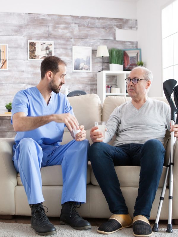 young-male-nurse-in-nursing-home-with-pills-for-senior-man-3.jpg